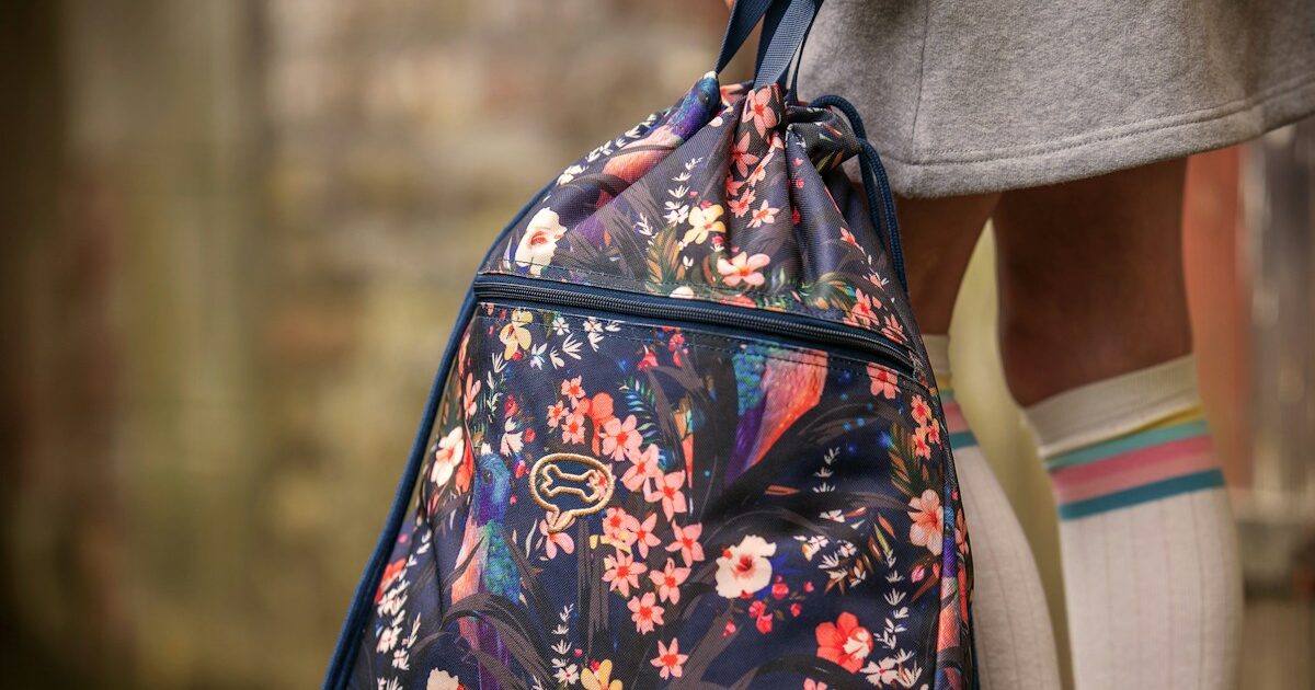 A girl holds a floral drawstring backpack.