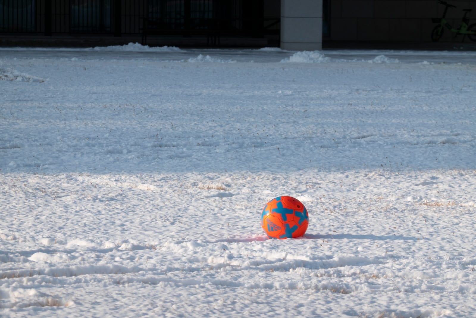 an orange and blue ball sitting in the snow